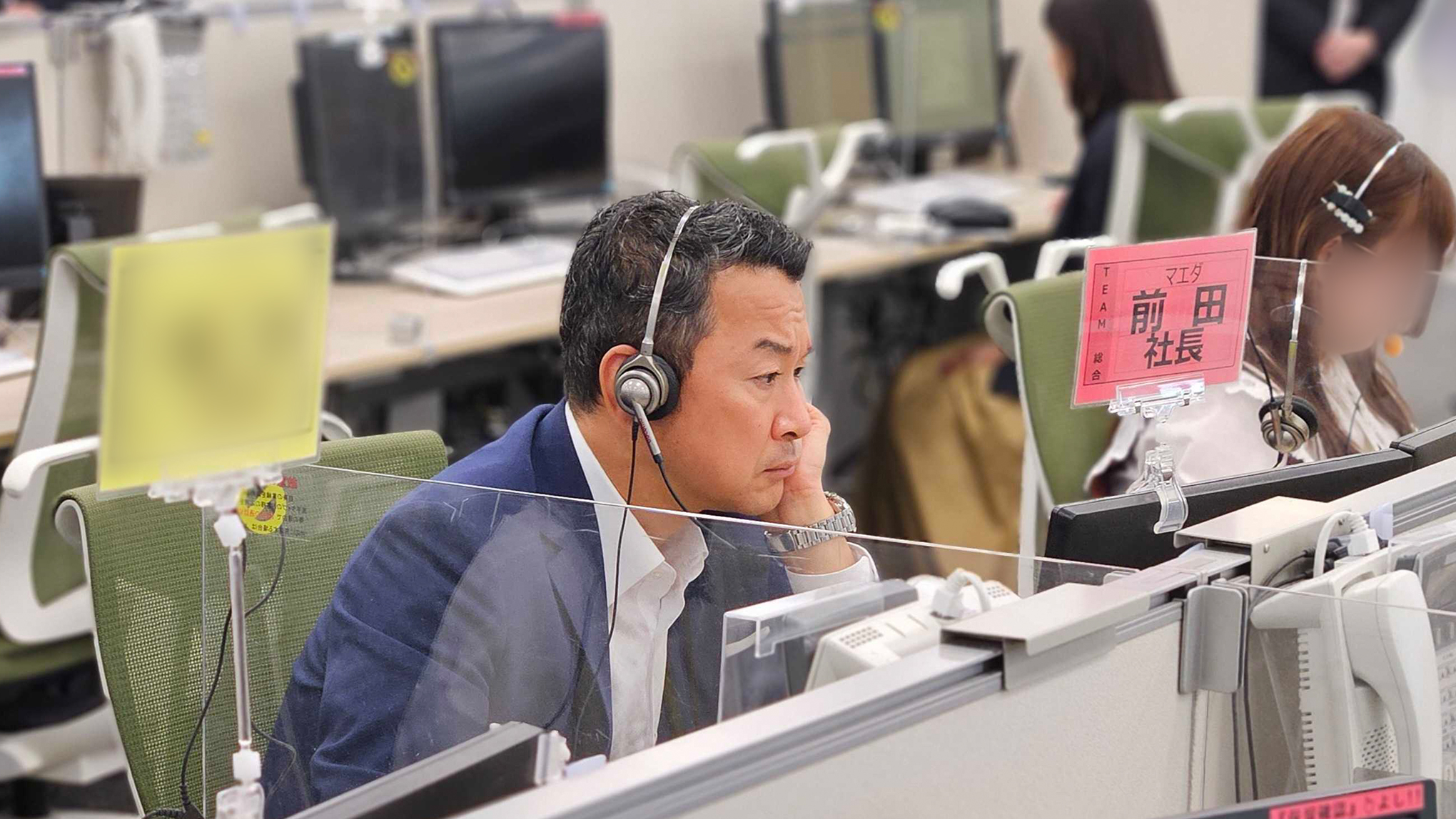 前田社長がインカムを着用して座席に座っている