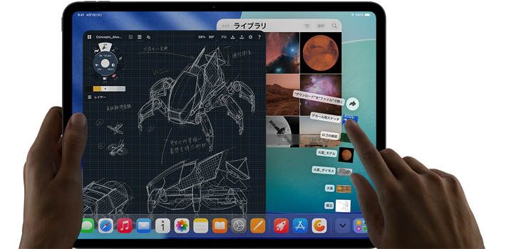 iPad Pro、カラーはスペースブラック、左手でデバイスを持ち、右手で複数の開いているアプリのウインドウを指差して操作するジェスチャーをしている。描画アプリと機械設計のスケッチ、惑星や宇宙の画像が保存された写真ライブラリ、扇状に広がったダウンロードフォルダ内のファイル