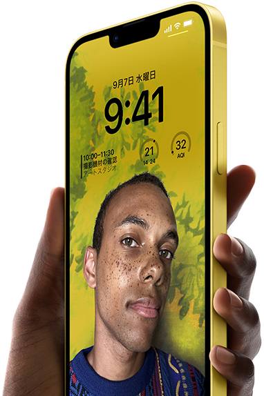 A hand holding an iPhone 14 Plus in yellow displaying a personalized Lock Screen.