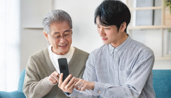 祖父と一緒にらくらくホンを見る孫