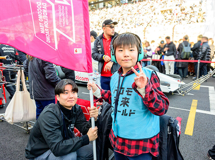 ダンディライアンレーシング | 2025 ドコモ未来フィールド | フラッグやパラソルを掲げている子どもたち